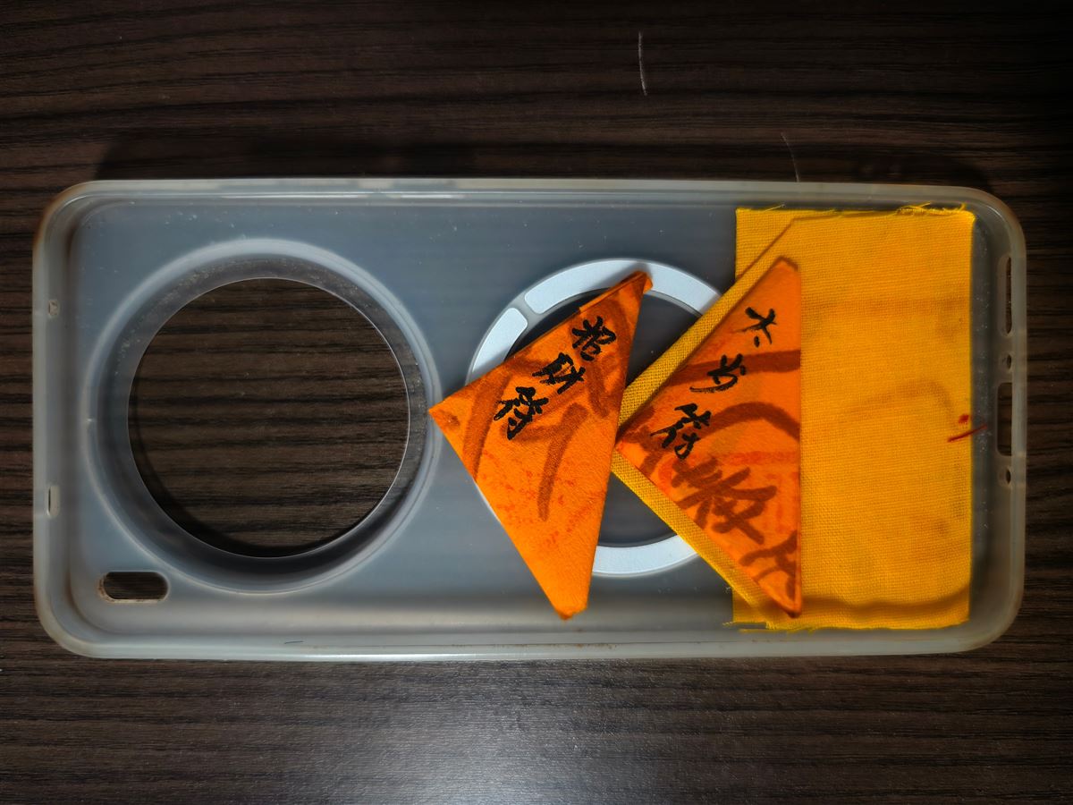 Hand-written temple talismans in a phone case - a wealth charm, a Tai Sui charm and a peace charm, a real Ben Ming Nian custom