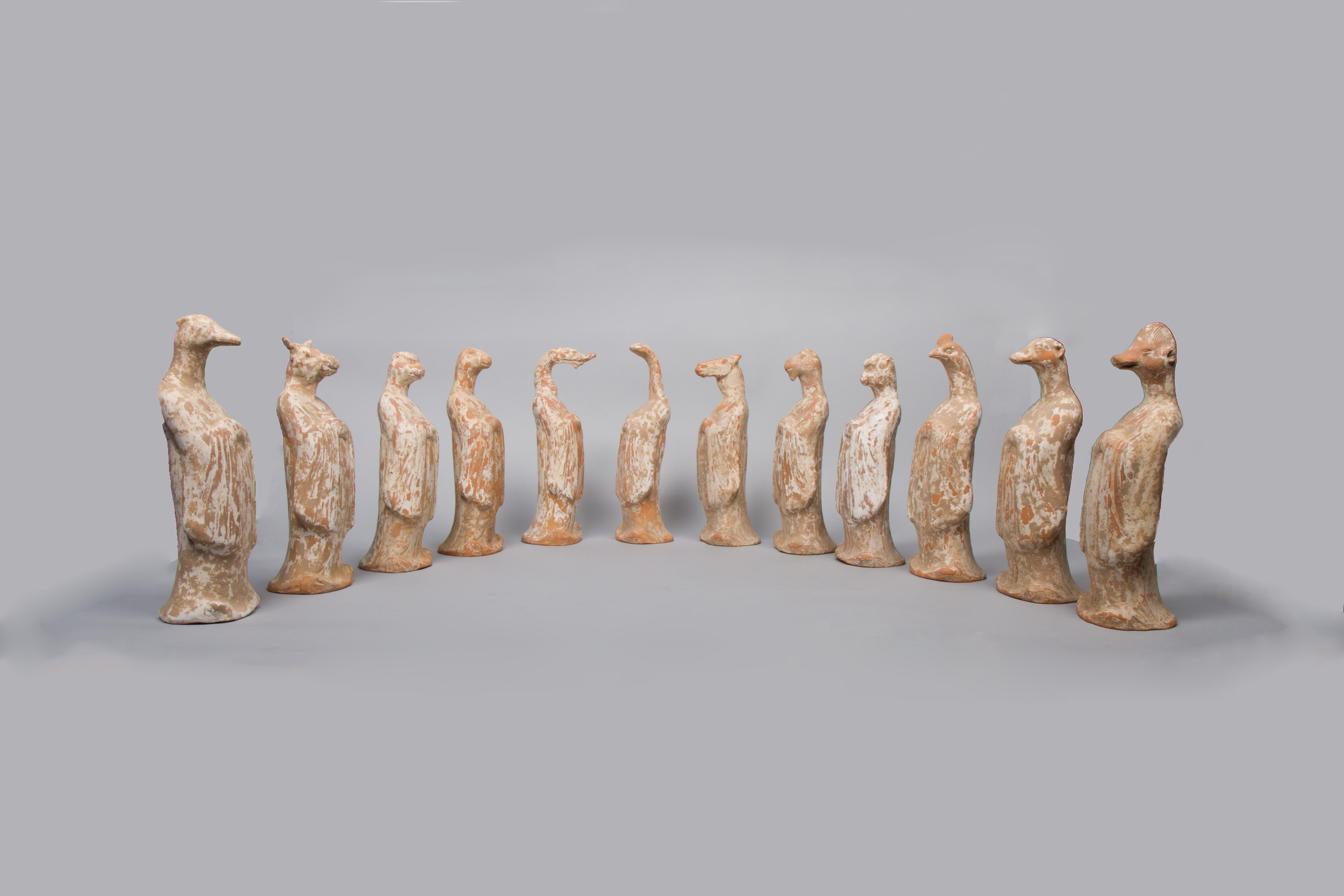 Twelve earthenware zodiac figures with animal heads and human bodies arranged in a semicircle.